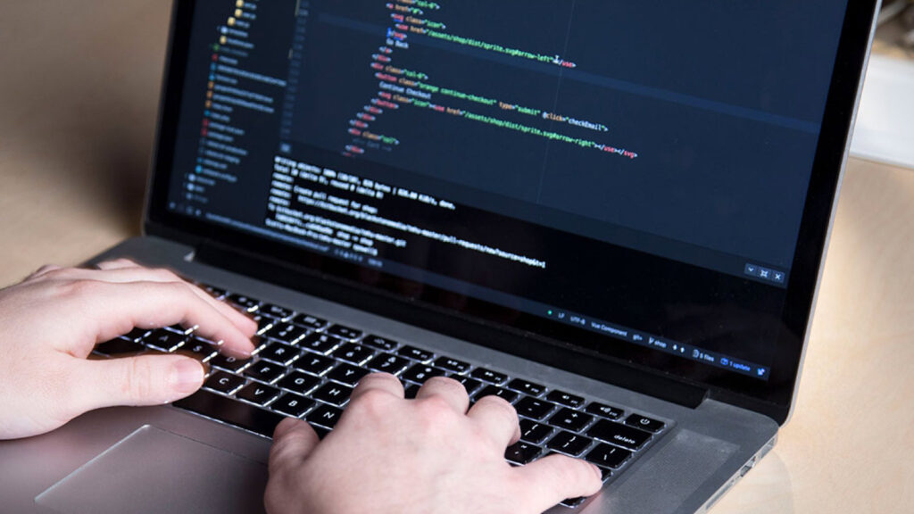 hands typing code on a MacBook Pro laptop.